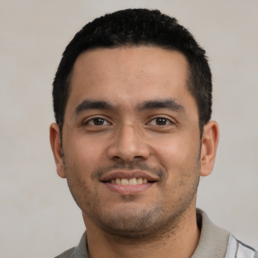 Joyful latino young-adult male with short  black hair and brown eyes