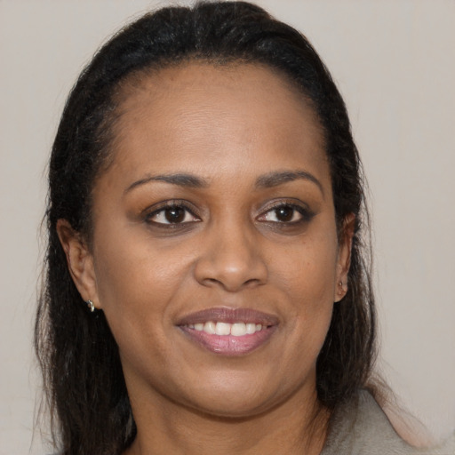Joyful black young-adult female with long  brown hair and brown eyes