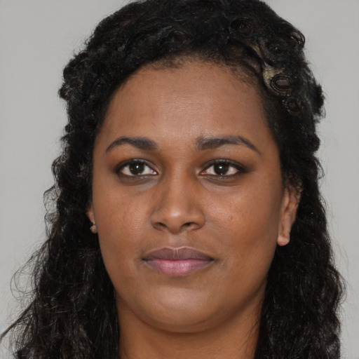 Joyful black young-adult female with long  black hair and brown eyes