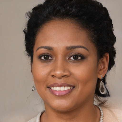 Joyful black young-adult female with long  black hair and brown eyes