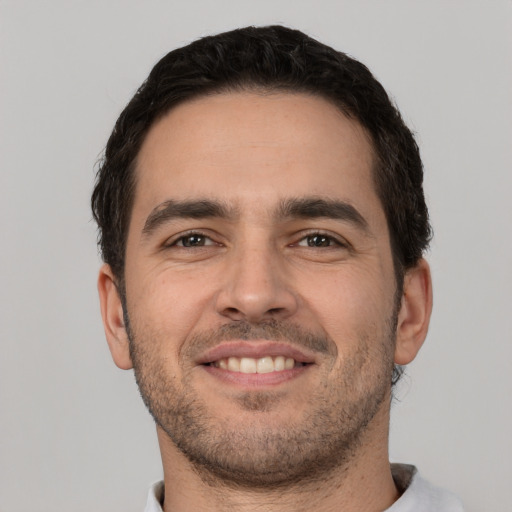 Joyful white young-adult male with short  black hair and brown eyes