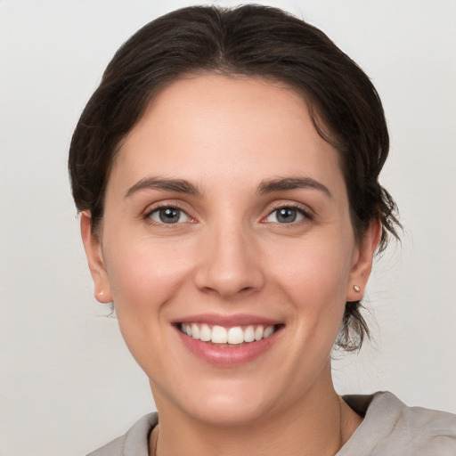 Joyful white young-adult female with medium  brown hair and grey eyes