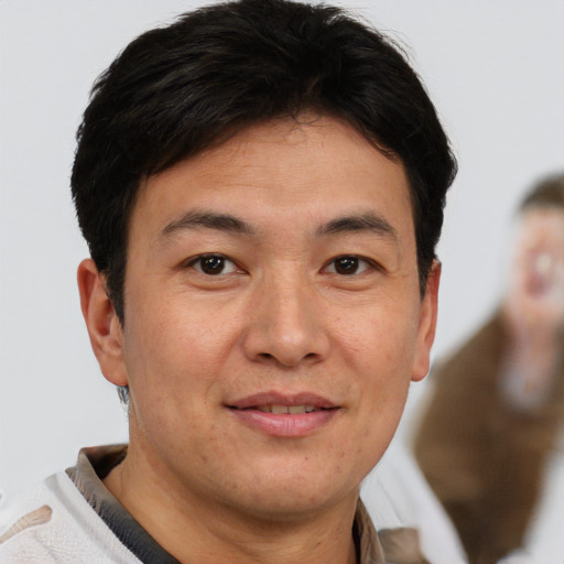 Joyful asian adult male with short  brown hair and brown eyes