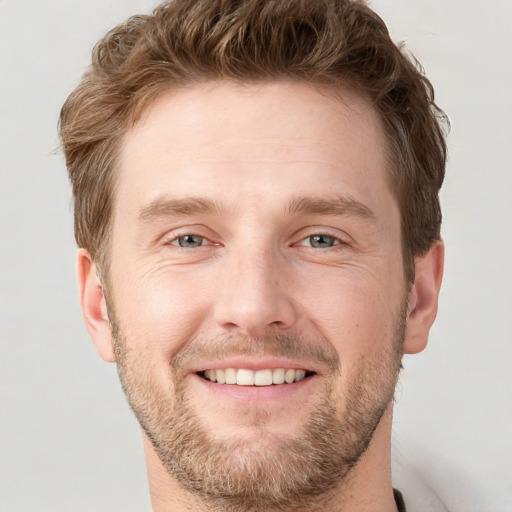 Joyful white young-adult male with short  brown hair and grey eyes