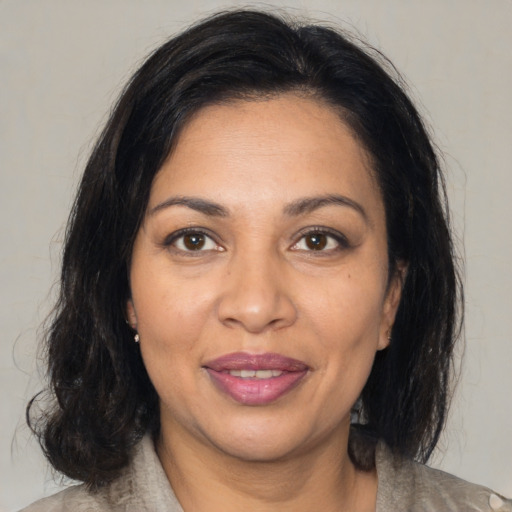 Joyful latino adult female with medium  brown hair and brown eyes