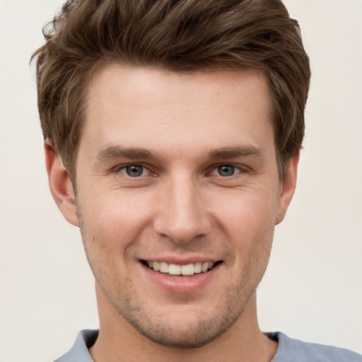 Joyful white young-adult male with short  brown hair and grey eyes