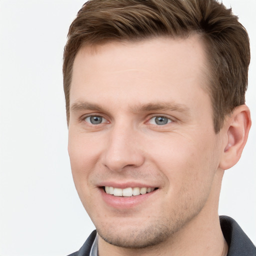 Joyful white young-adult male with short  brown hair and grey eyes