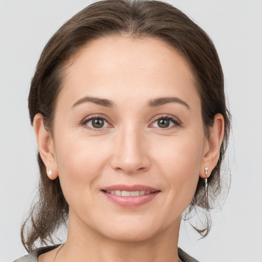 Joyful white young-adult female with medium  brown hair and grey eyes