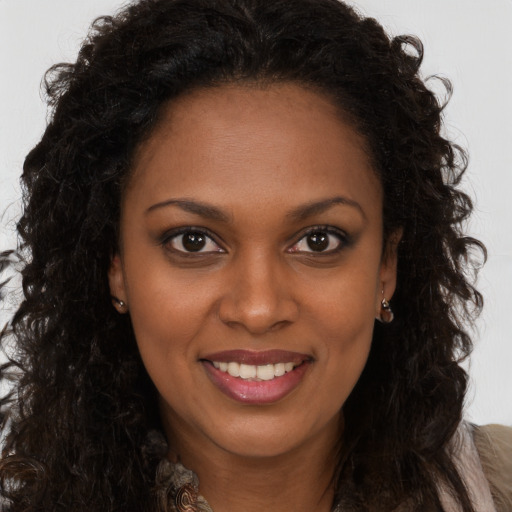 Joyful black young-adult female with long  brown hair and brown eyes