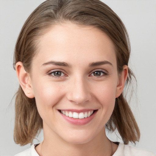 Joyful white young-adult female with medium  brown hair and grey eyes