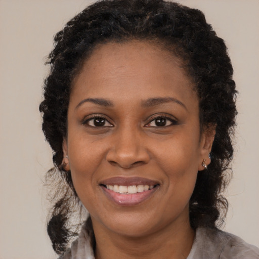 Joyful black young-adult female with long  black hair and brown eyes