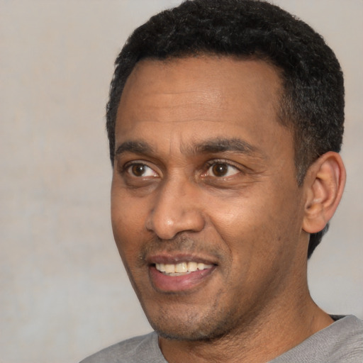 Joyful black adult male with short  black hair and brown eyes