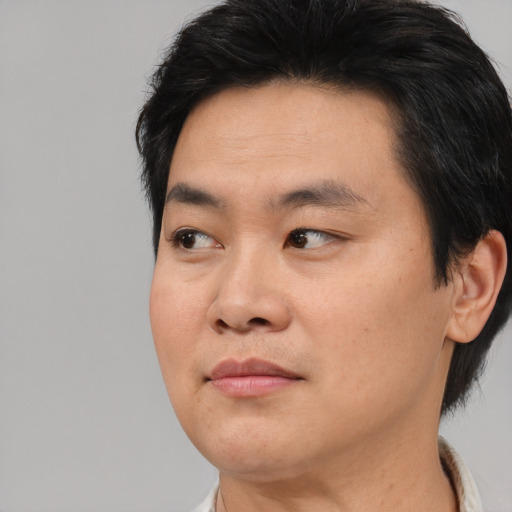 Joyful asian young-adult male with short  black hair and brown eyes