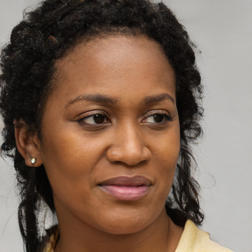 Joyful black young-adult female with long  brown hair and brown eyes