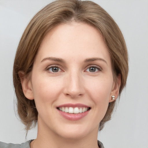 Joyful white young-adult female with medium  brown hair and grey eyes