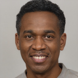 Joyful black adult male with short  black hair and brown eyes