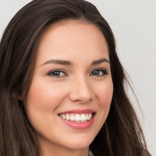 Joyful white young-adult female with long  brown hair and brown eyes