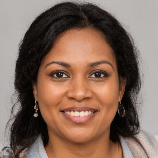 Joyful black young-adult female with long  brown hair and brown eyes