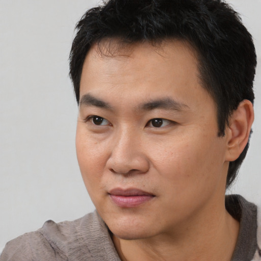 Joyful asian young-adult male with short  black hair and brown eyes