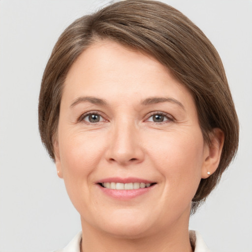 Joyful white young-adult female with medium  brown hair and grey eyes