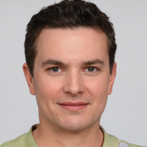 Joyful white young-adult male with short  brown hair and grey eyes