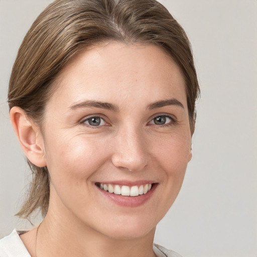 Joyful white young-adult female with medium  brown hair and grey eyes