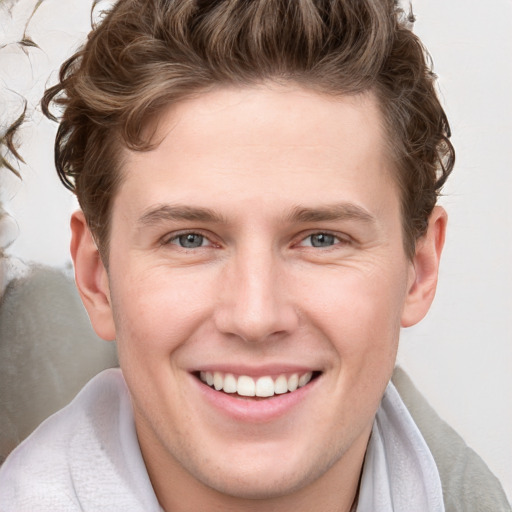 Joyful white young-adult male with short  brown hair and blue eyes