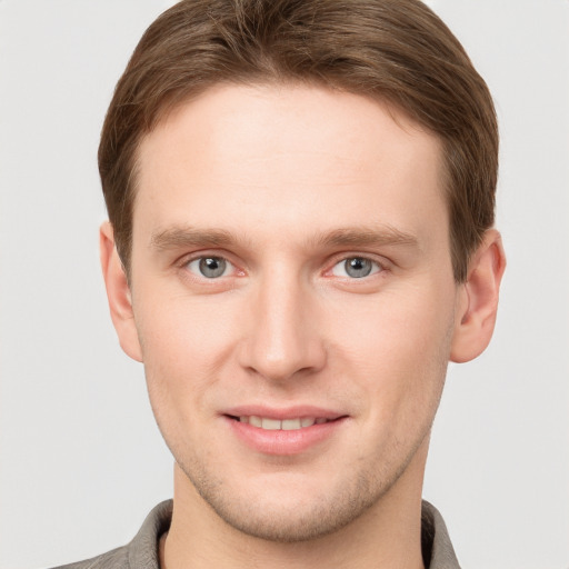 Joyful white young-adult male with short  brown hair and grey eyes