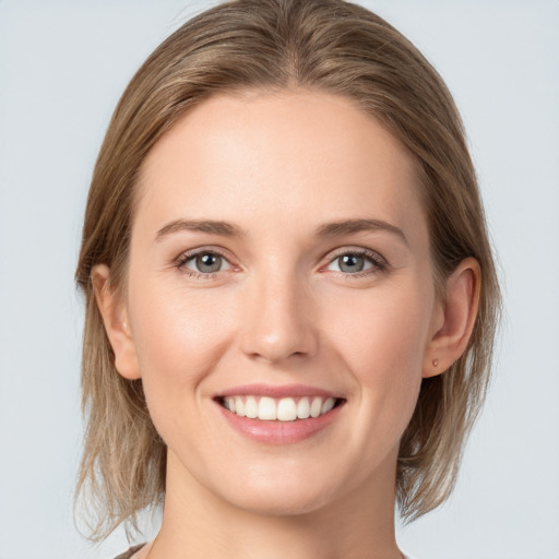 Joyful white young-adult female with medium  brown hair and grey eyes