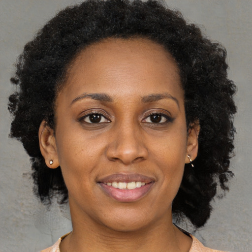 Joyful black young-adult female with long  brown hair and brown eyes