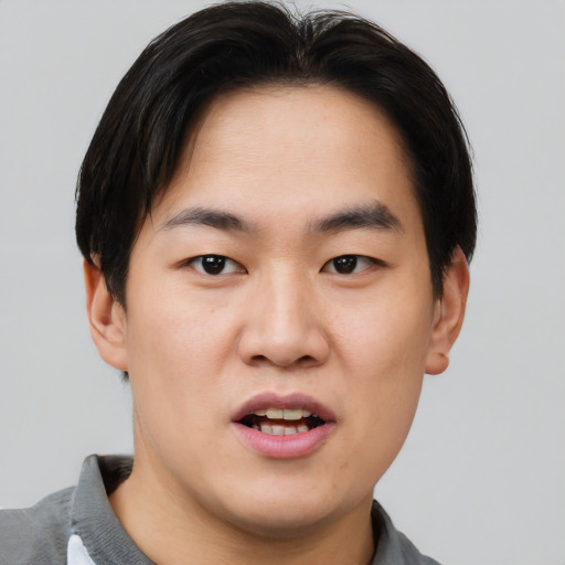 Joyful asian young-adult male with short  brown hair and brown eyes