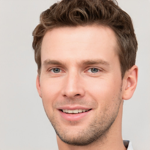 Joyful white young-adult male with short  brown hair and grey eyes