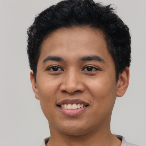 Joyful latino young-adult male with short  black hair and brown eyes
