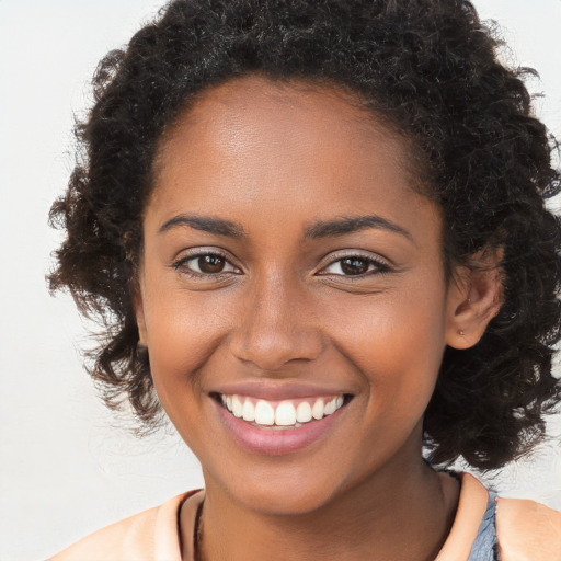 Joyful black young-adult female with long  brown hair and brown eyes