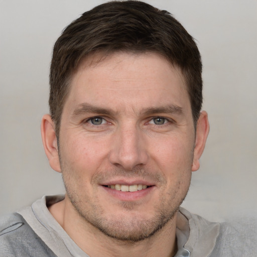 Joyful white young-adult male with short  brown hair and grey eyes