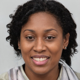 Joyful black young-adult female with long  brown hair and brown eyes