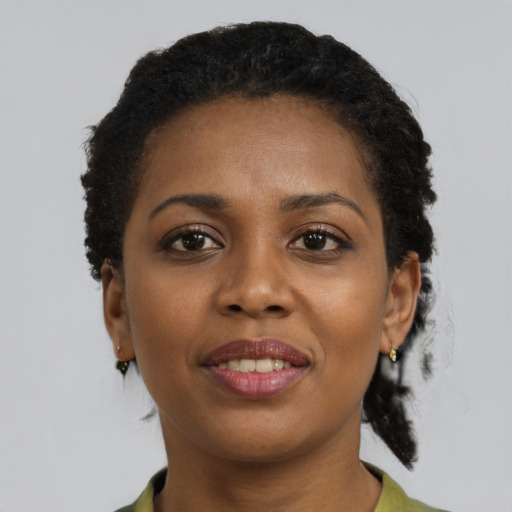 Joyful black young-adult female with short  black hair and brown eyes