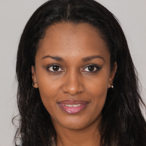 Joyful black young-adult female with long  brown hair and brown eyes