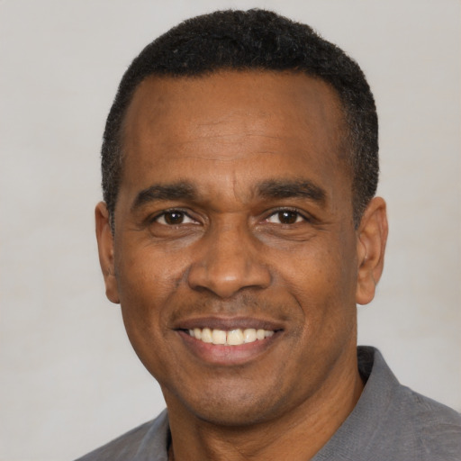 Joyful black adult male with short  black hair and brown eyes