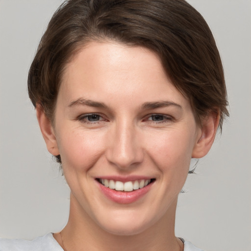 Joyful white young-adult female with medium  brown hair and grey eyes