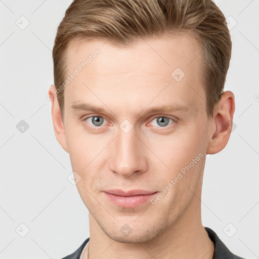 Joyful white young-adult male with short  brown hair and grey eyes