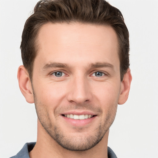 Joyful white young-adult male with short  brown hair and grey eyes