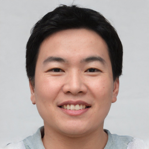 Joyful asian young-adult male with short  black hair and brown eyes