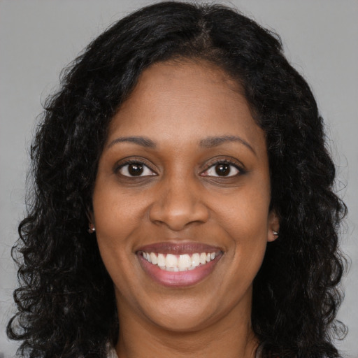 Joyful black young-adult female with long  brown hair and brown eyes
