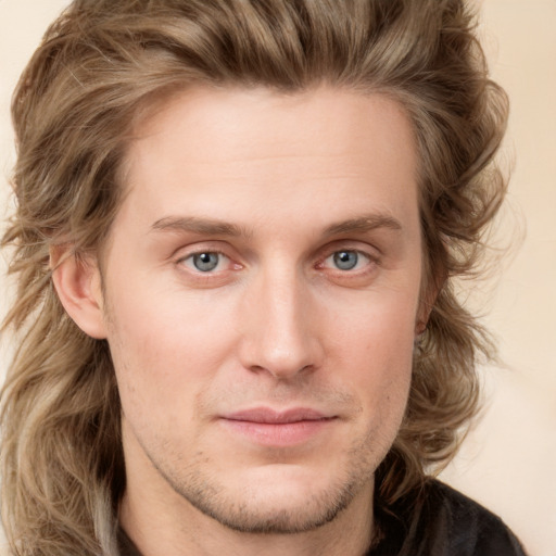 Joyful white young-adult male with long  brown hair and blue eyes