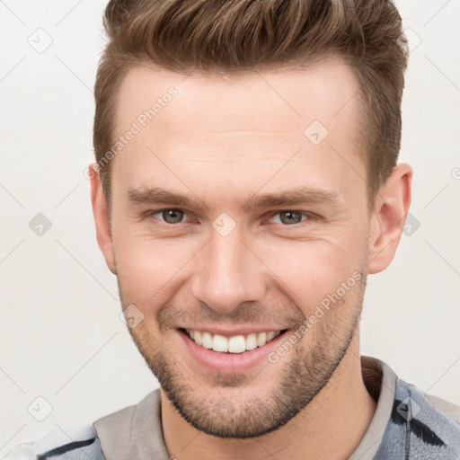 Joyful white young-adult male with short  brown hair and grey eyes