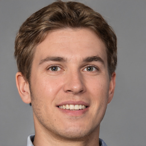 Joyful white young-adult male with short  brown hair and grey eyes