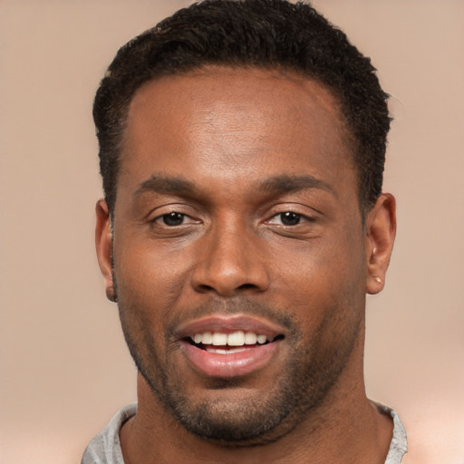 Joyful black young-adult male with short  brown hair and brown eyes