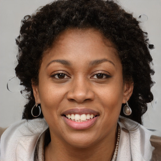 Joyful black young-adult female with long  brown hair and brown eyes