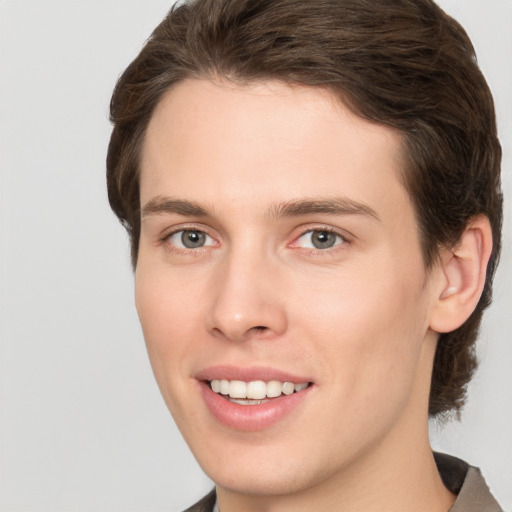 Joyful white young-adult male with medium  brown hair and grey eyes